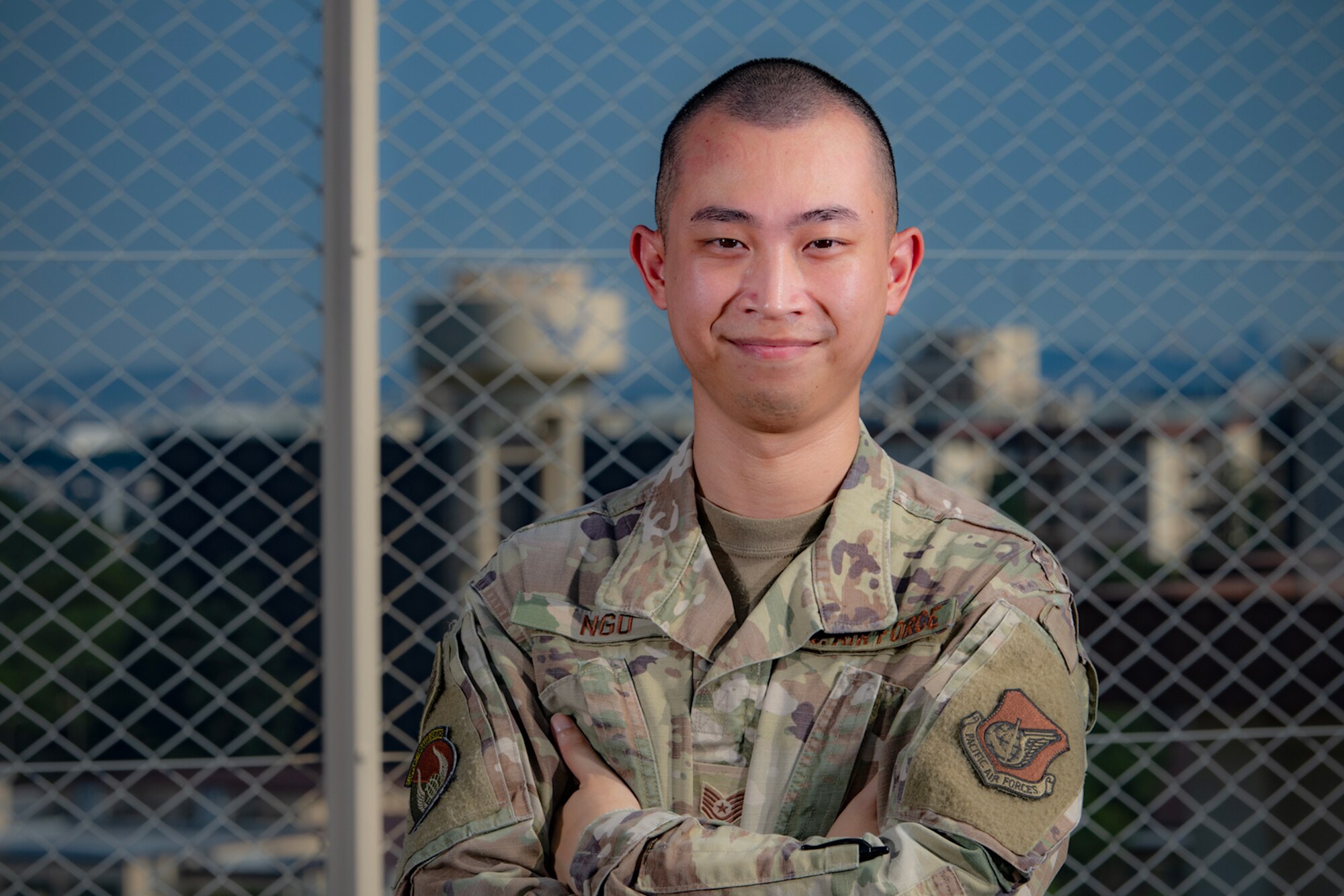 Military man stands with arms crossed.