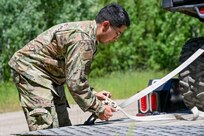 An Airman tightens a vehicle to a trailer