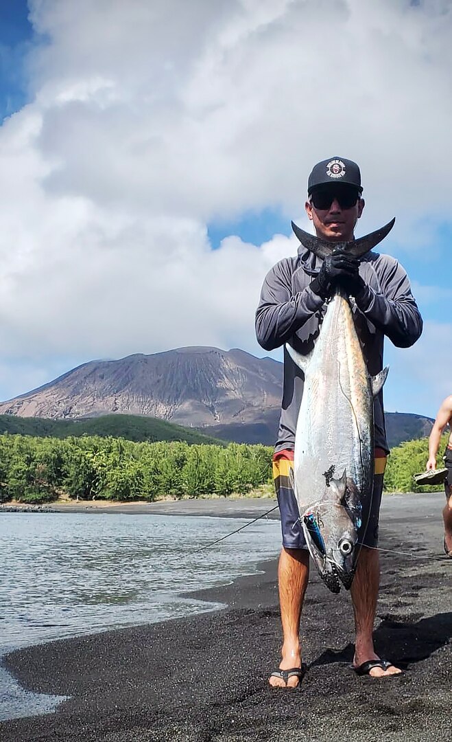 Petty Officer 1st Class Ikaika Ruiz of the USCGC Oliver Henry (WPC 1140) stands with a tuna he caught from shore in the Northern Mariana Islands on May 17, 2023. Originally from Hawaii, Ruiz is an engineer aboard the ship specializing as an electrician. (U.S. Coast Guard photo)