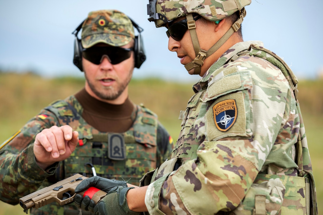 A soldier gets instructions on a gun from another soldier.