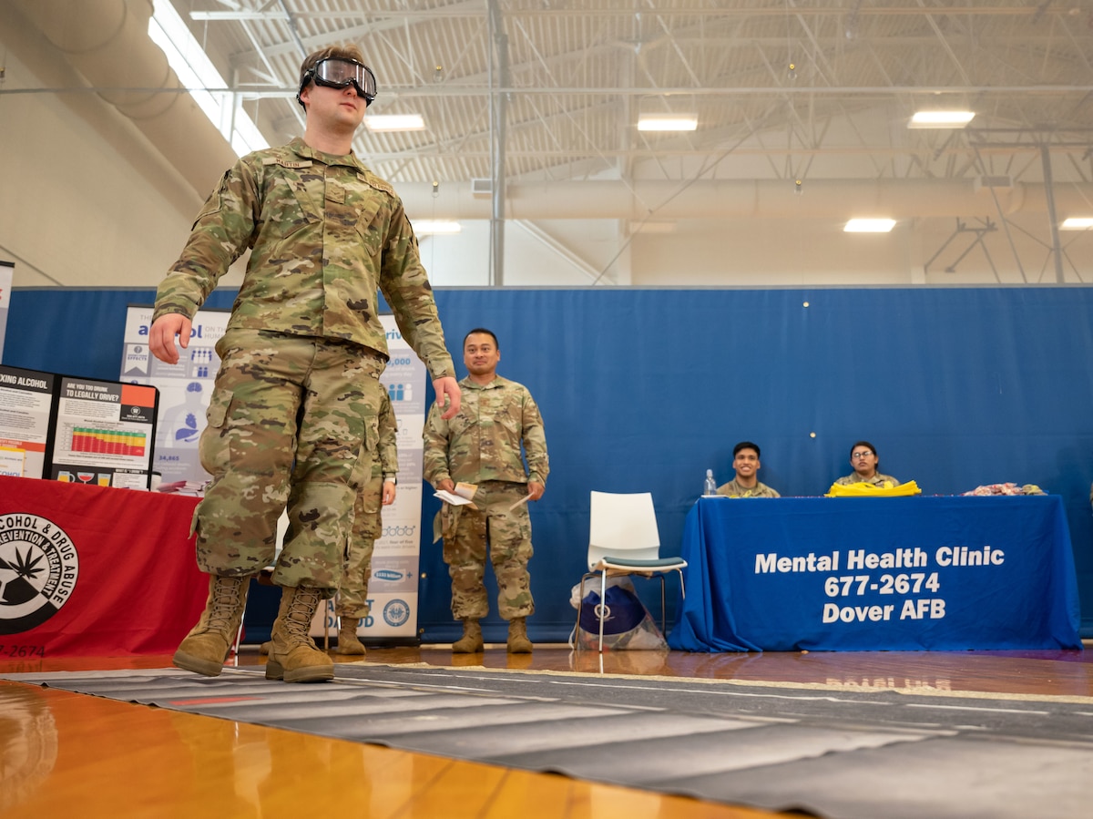 Airman 1st Class Wesley Martin, 436th Airlift Wing Judge Advocate paralegal, attempts to walk in a straight line while wearing simulated drunk driving goggles during the 436th Force Support Squadron Health and Wellness Fair at Dover Air Force Base, Delaware, July 26, 2023. The event featured various military and civilian organizations focused on providing health resources to Airmen. (U.S. Air Force photo by Senior Airman Cydney Lee)