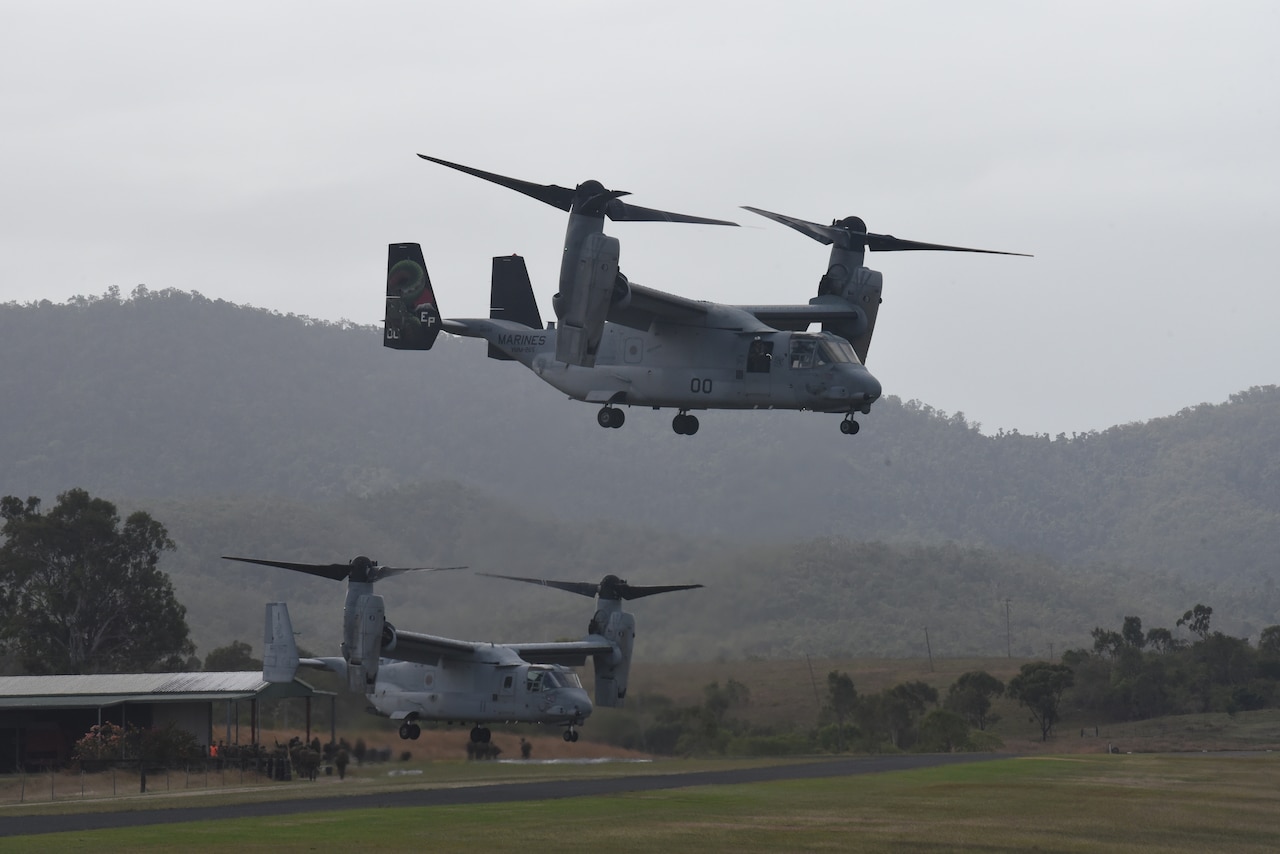 Two military aircraft land in a field.