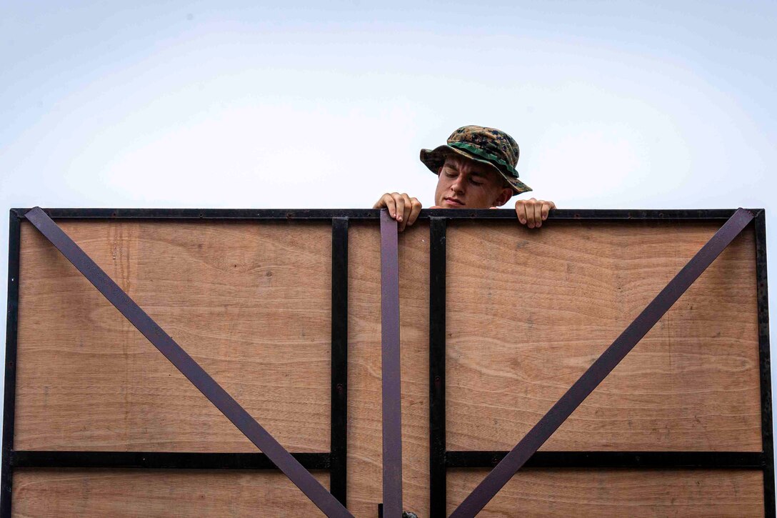 A Marine works on the backboard of a basketball hoop.