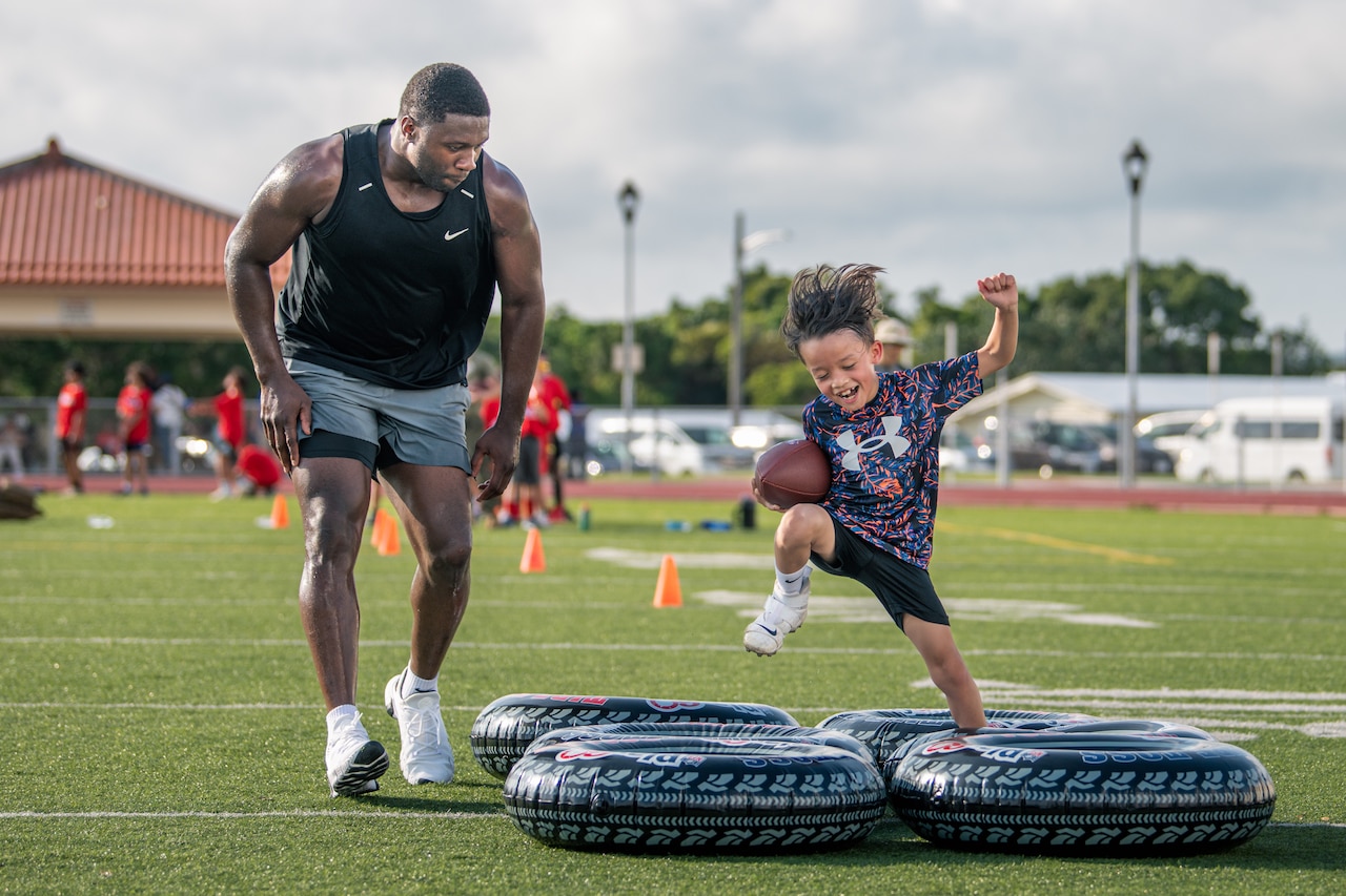 A man runs beside a boy as he cheerfully runs through a gauntlet of inflated inner tubes.