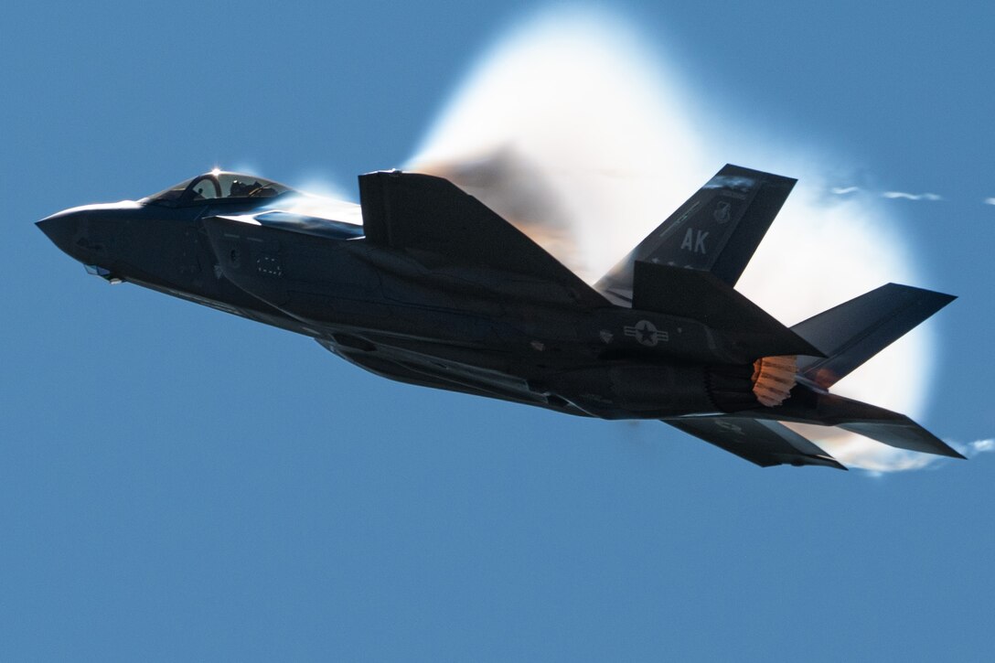 A fighter jet flies against a blue sky.