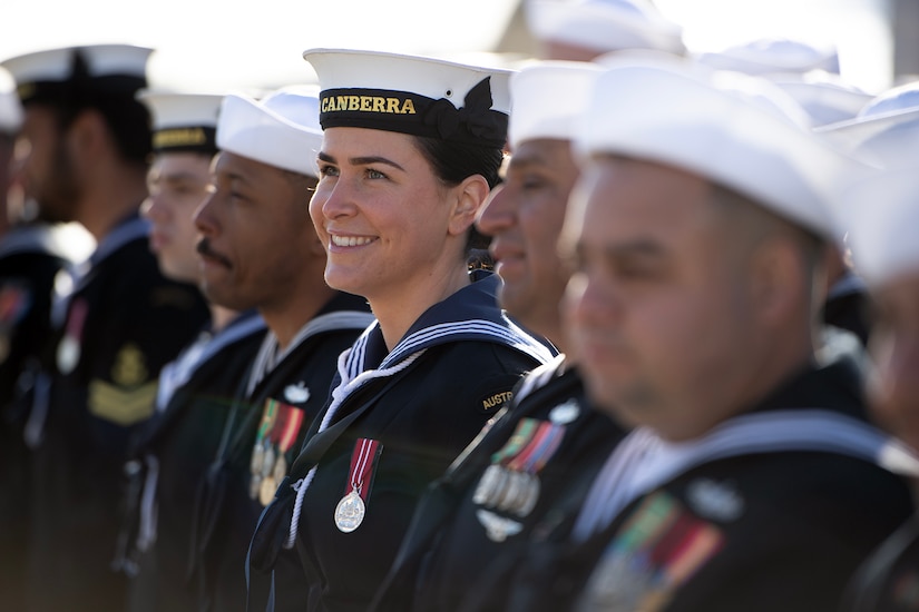 Sailors stand in formation as one smiles.
