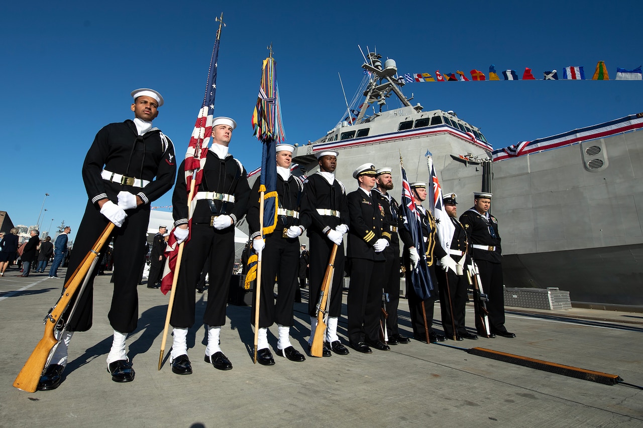 U.S. and Australian ceremonial guard members pose for a photo next to a ship.