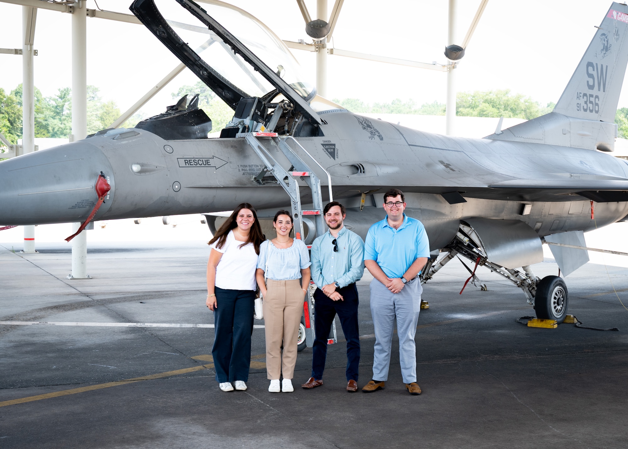 Four legislative assistants stand in front of an F-16C Fighting Falcon under a hangar at Shaw Air Force Base, S.C.
