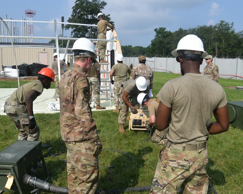 Military members in uniform prepare electrical systems.