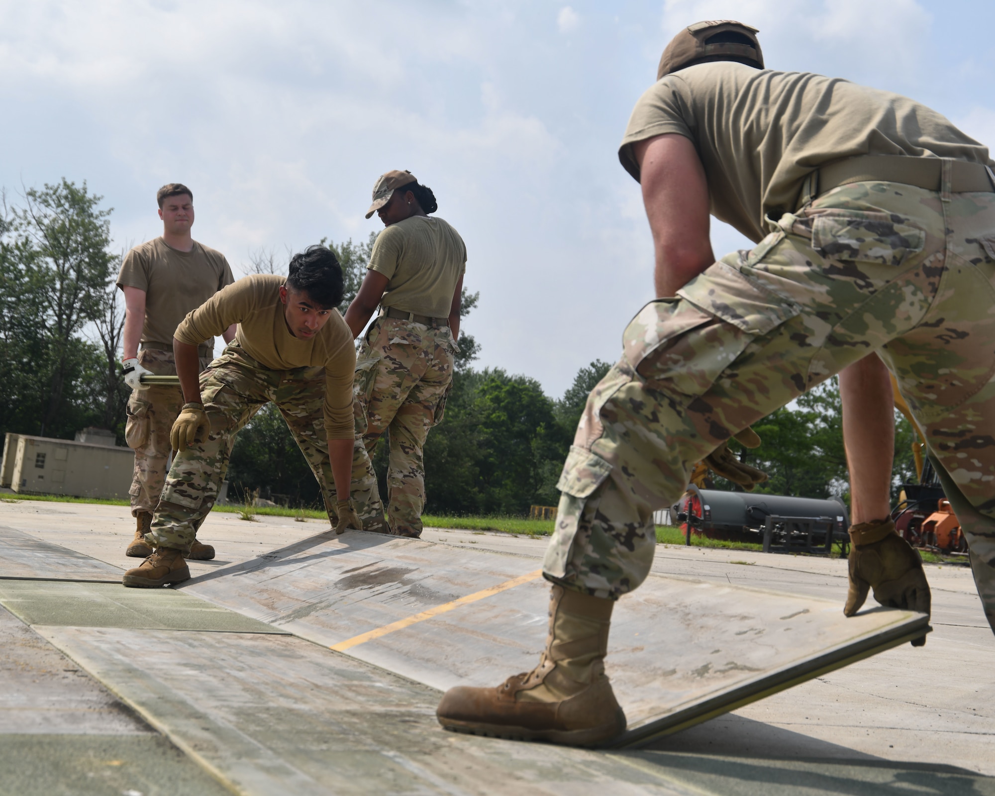Military members in uniform lay down boards.