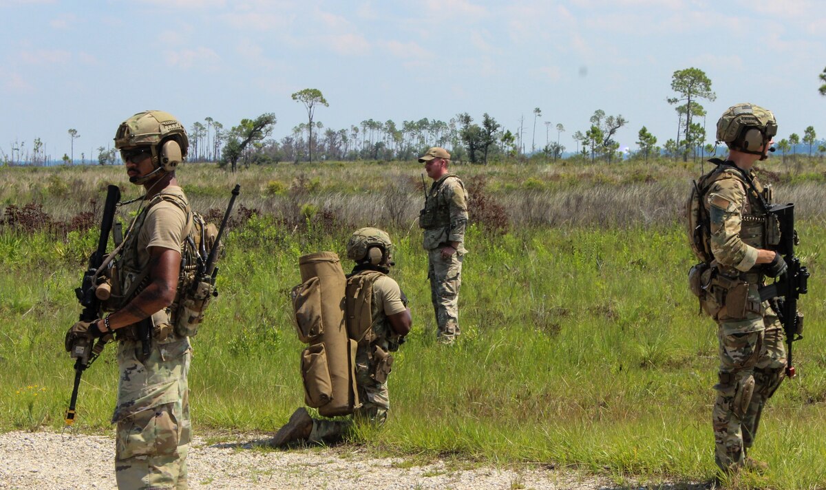 A security forces squad watches for "combatants" in a field