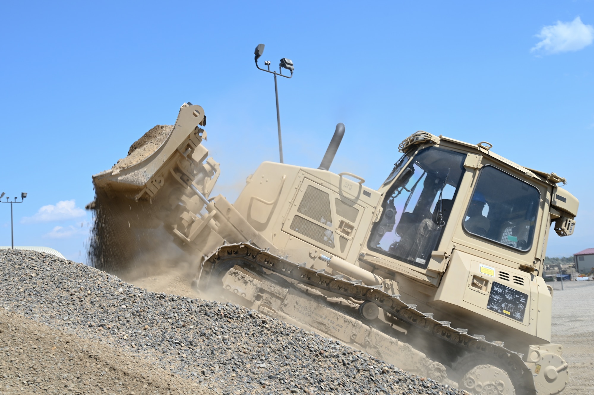 Senior Airman Jonathan Edwards, 131st Civil Engineer Squadron heavy equipment operator, operates a bulldozer to consolidate stockpile material for a building under construction at Fort William Henry Harrison, Montana, July 25, 2023. The project provides an opportunity for 131st Airmen to develop skills and gain experience in their military jobs. (U.S. Air National Guard photo by Airman 1st Class Phoenix Lietch)