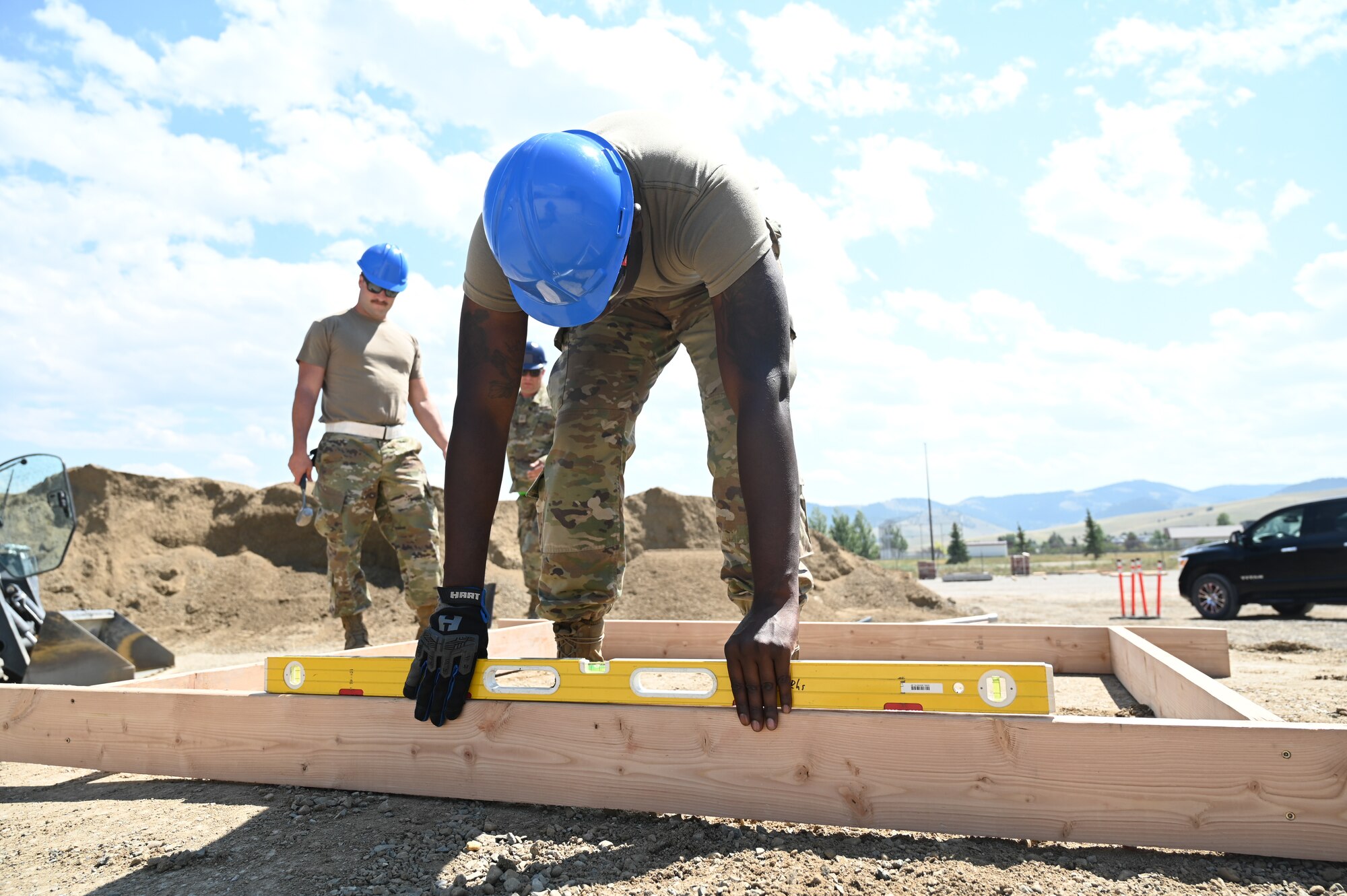 Senior Airman Jonathan Edwards, 131st Civil Engineer Squadron heavy equipment operator, ensures the level is correct for a concrete pad at Fort William Henry Harrison, Montana, July 25, 2023. The 131st, 819th Red Horse Squadron, and 219th Red Horse Squadron helped provide the Montana National Guard with a M1 Abrams tank storage facility to save taxpayer dollars. (U.S. Air National Guard photo by Airman 1st Class Phoenix Lietch)
