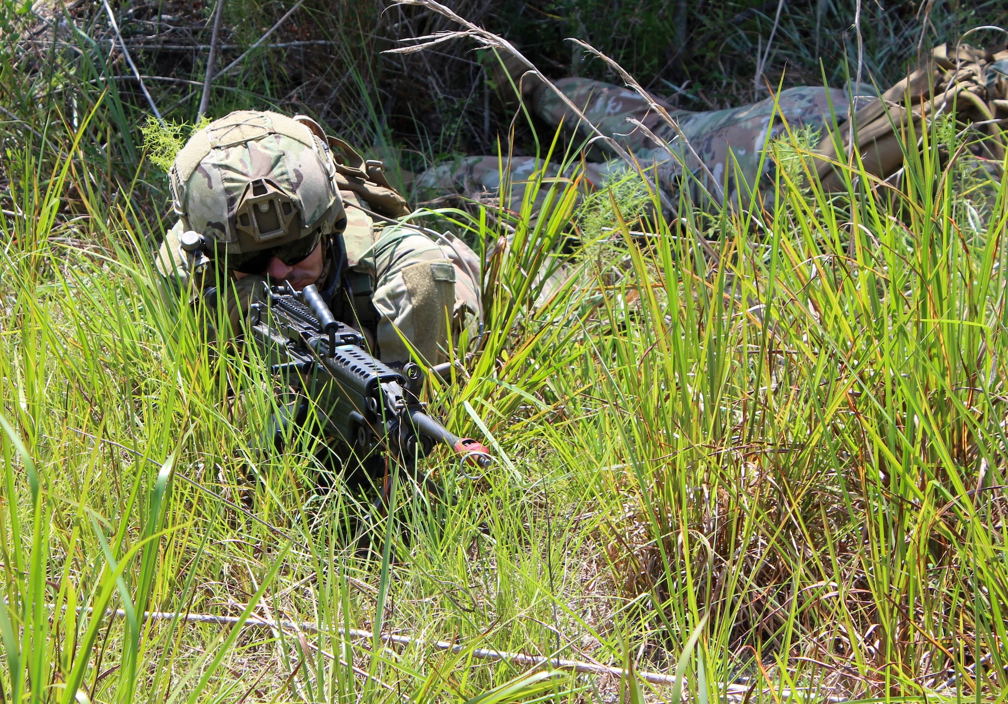 Airman laying in the brush with weapon ready