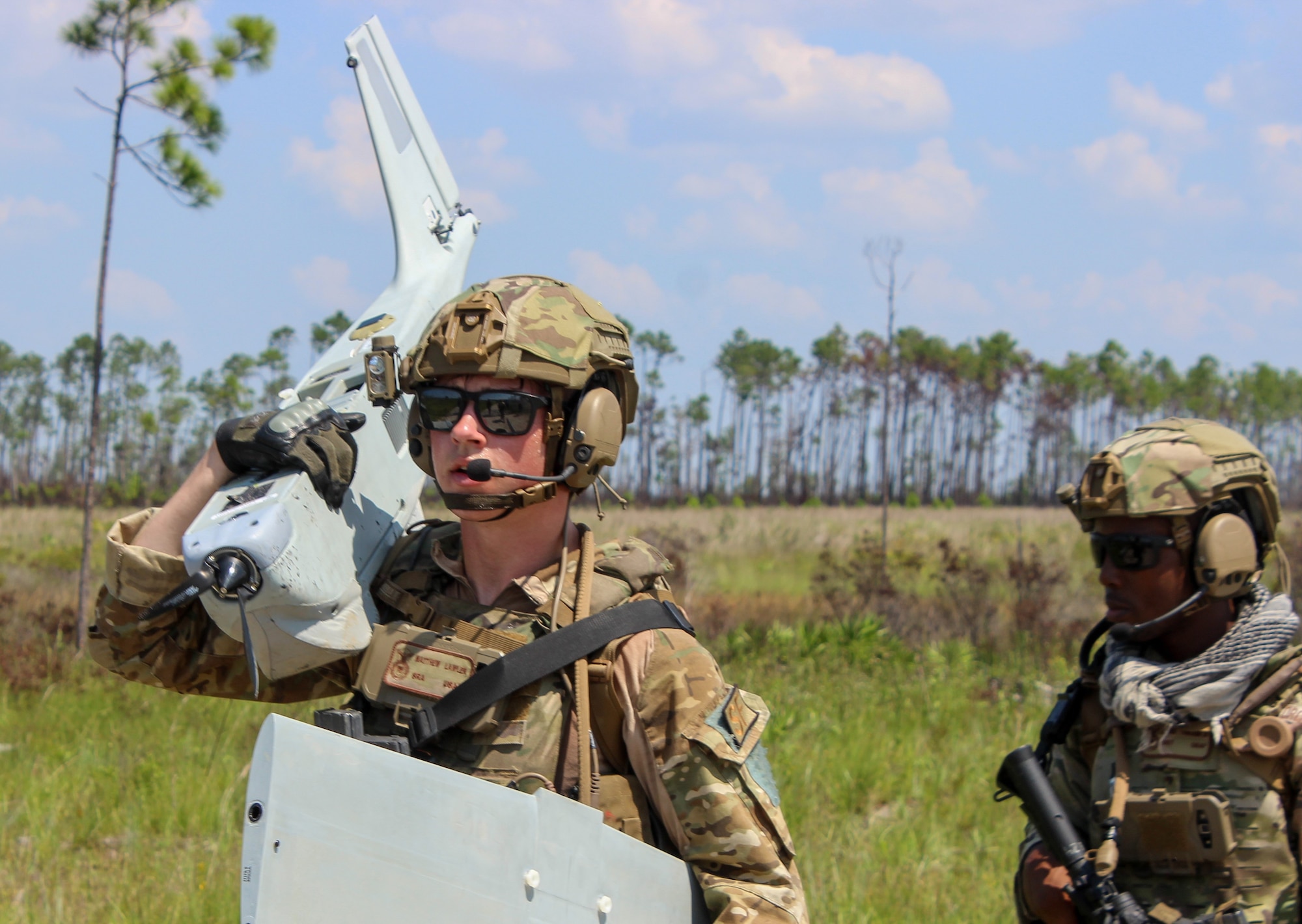 An Airman carries the wing and fuselage of a sUAS