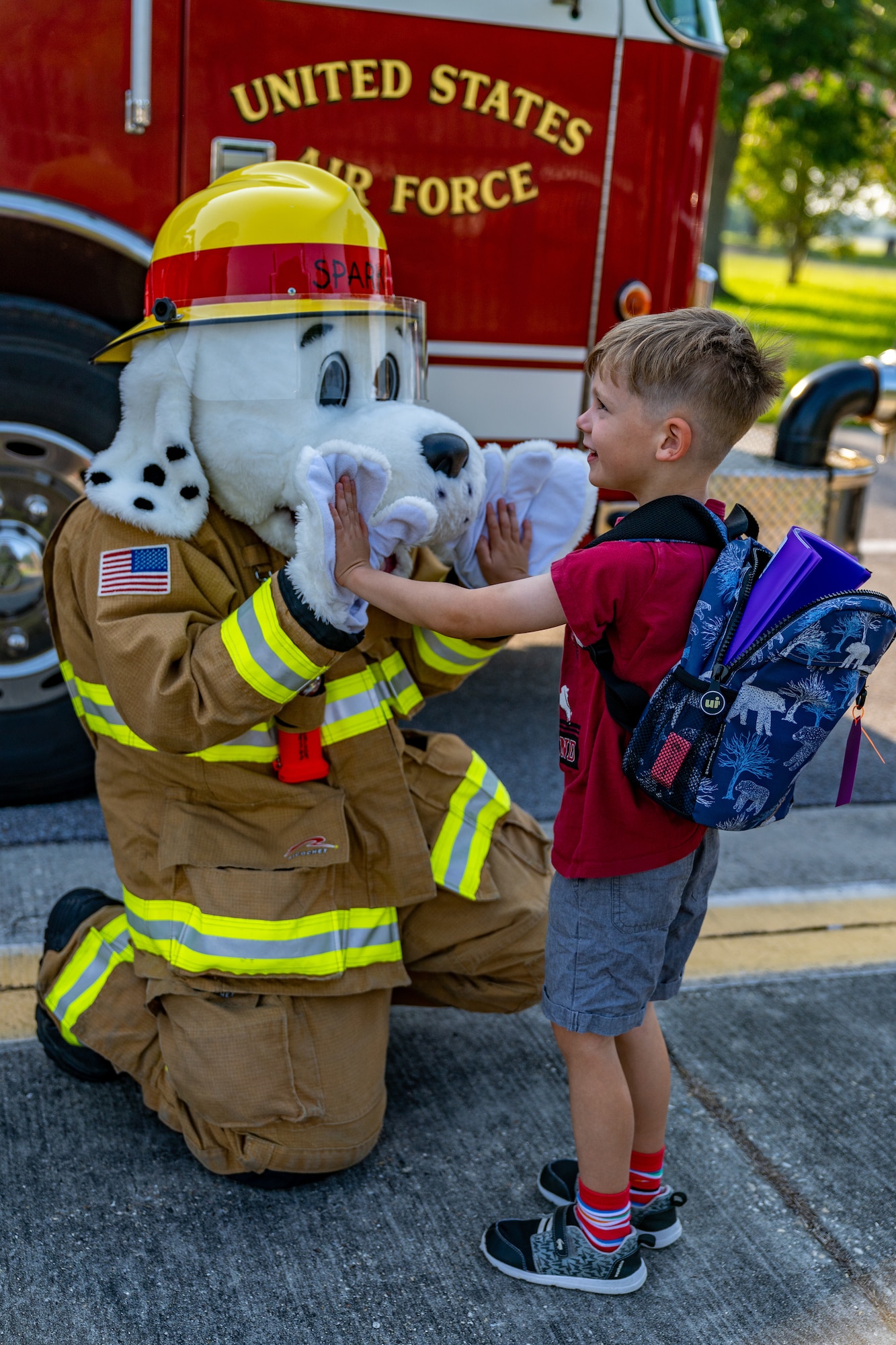 Sparky, Keesler Fire Department, high fives Ben Kuc, son of Lt. Col. Nicholas Kuc, 333rd Training Squadron commander, before his first day of school at Keesler Air Force Base, Mississippi, July 27, 2023.
