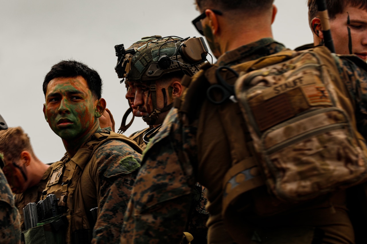 Service members wearing camouflage uniforms and face paint stand in a group.