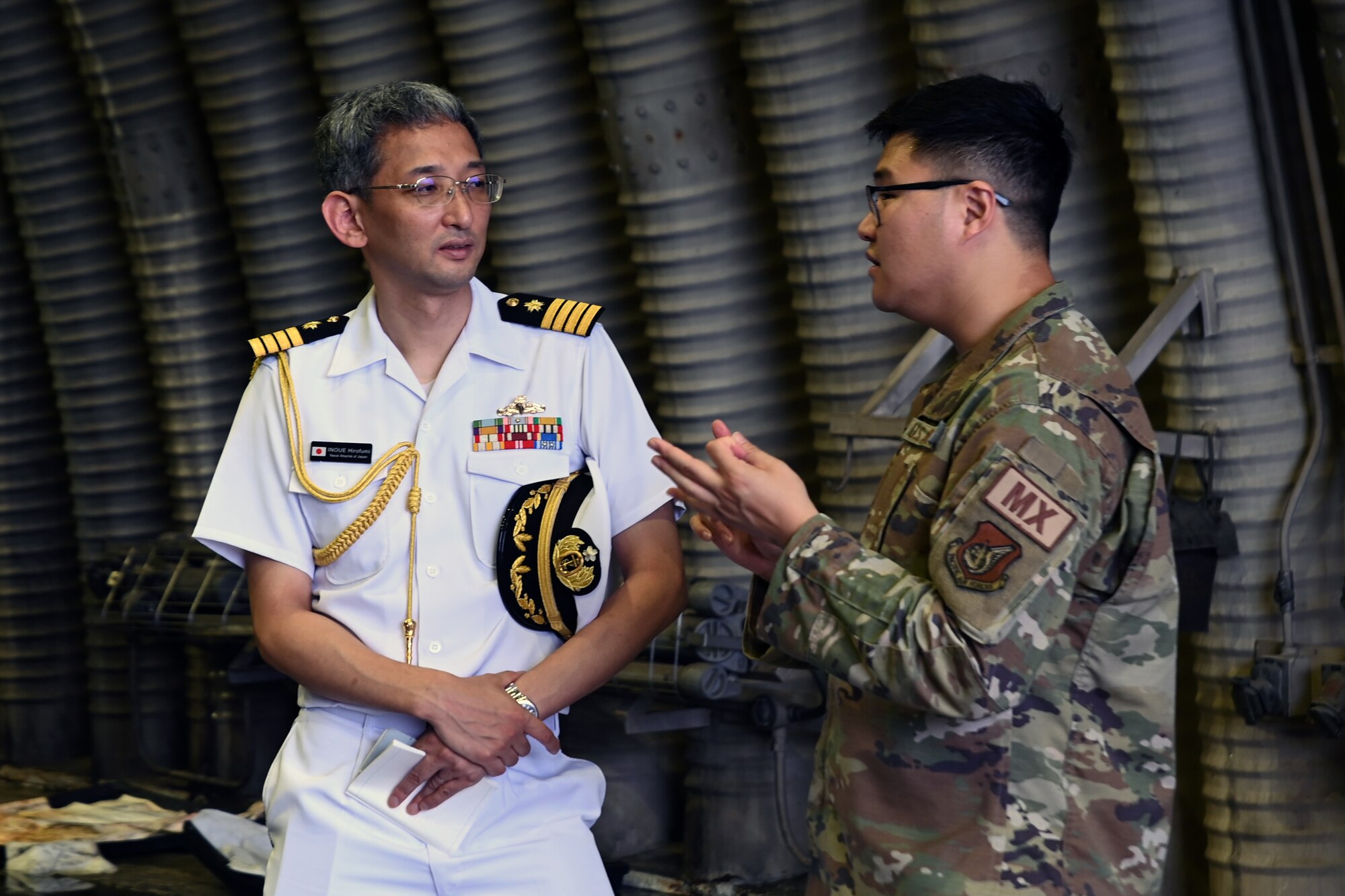 U.S. Air Force Capt. Sung Suh, right, 80th Fighter Generation Squadron, speaks with Naval Attaché of Japan Col. Hirofumi Inoue, a member of the Research Institute for Indo-Pacific Affairs, during a visit to Osan Air Base, Republic of Korea, July 18, 2023.