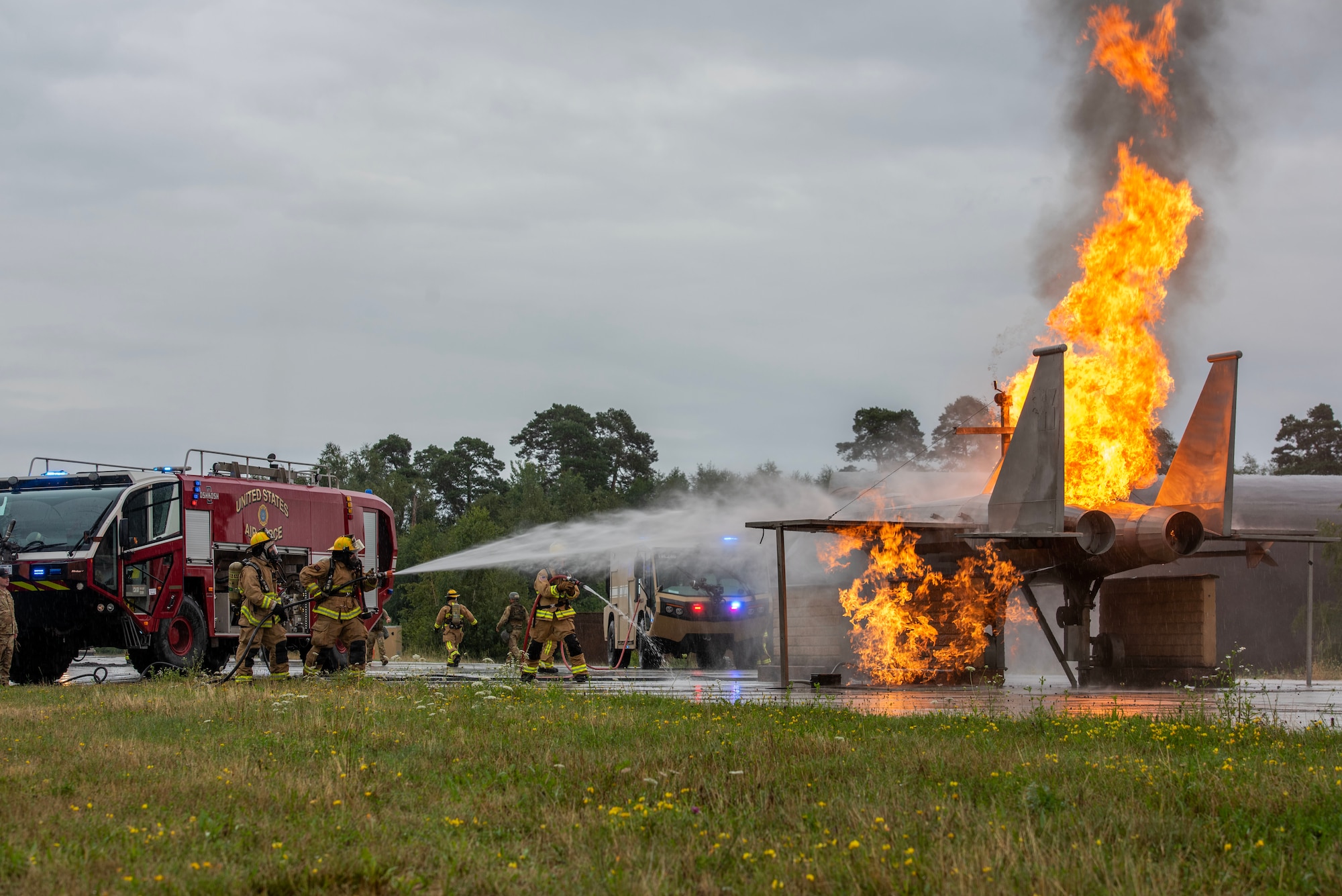 Firefighters use a hose to put out a fire on an F-15 replica