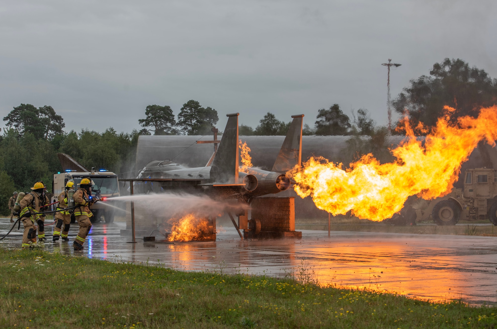 Firefighters use a hose to put out a controlled fire on an F-15 aircraft replica