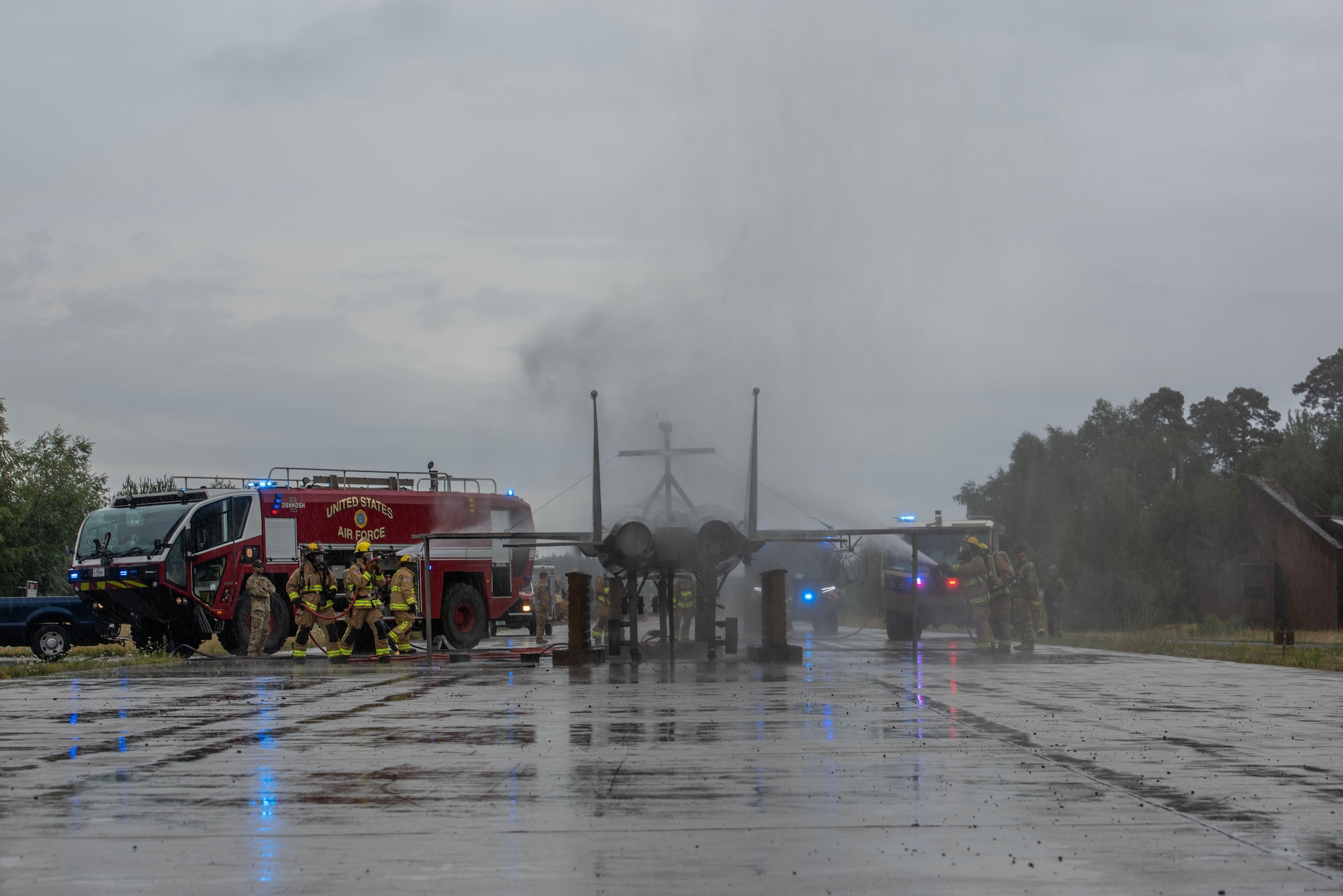 Firefighters use a hose to spray down an F-15 aircraft replica