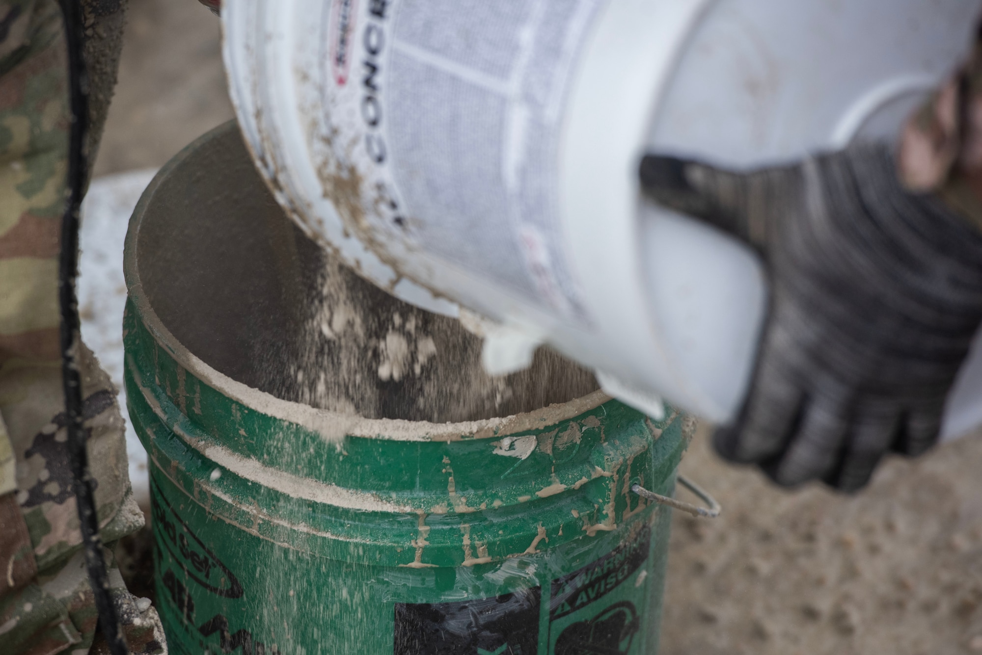 Man pours concrete powder into a bucket