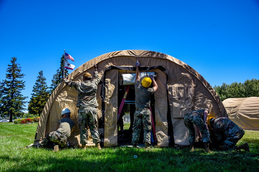 A group of airmen set up a large tent.