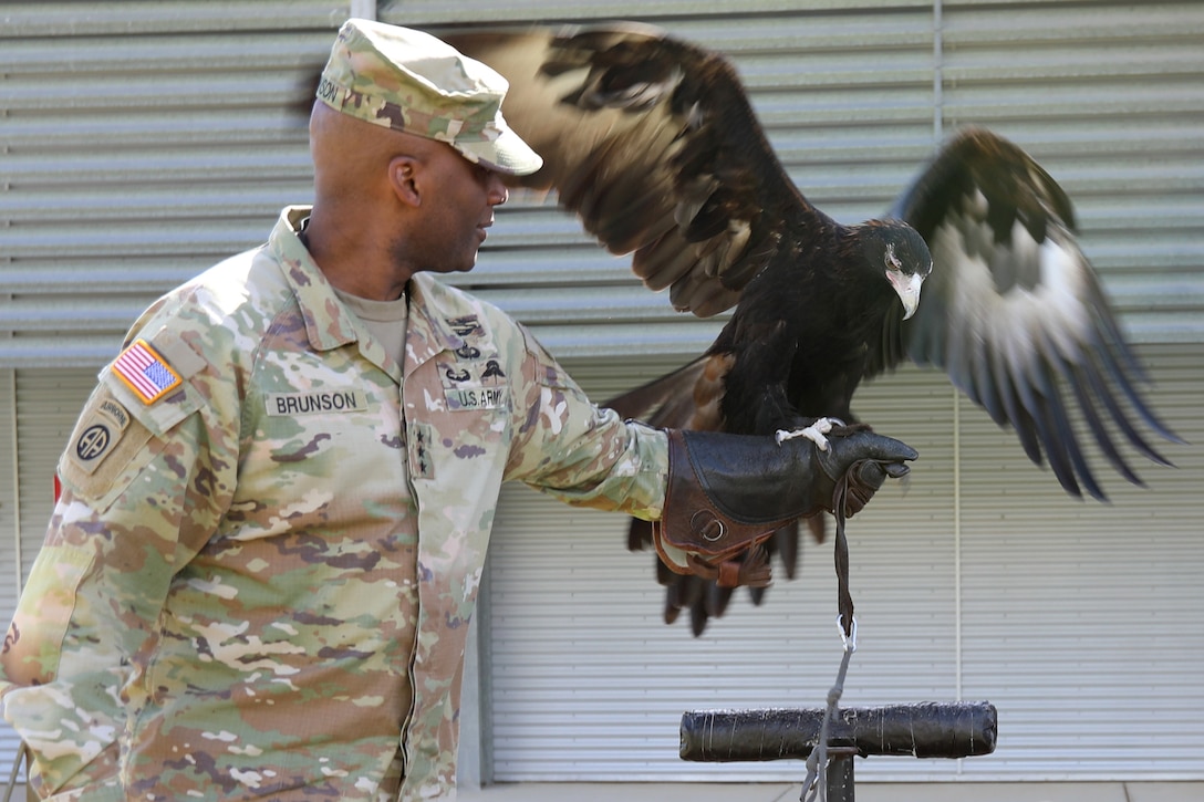 An Army officer  holds an eagle on his arm.