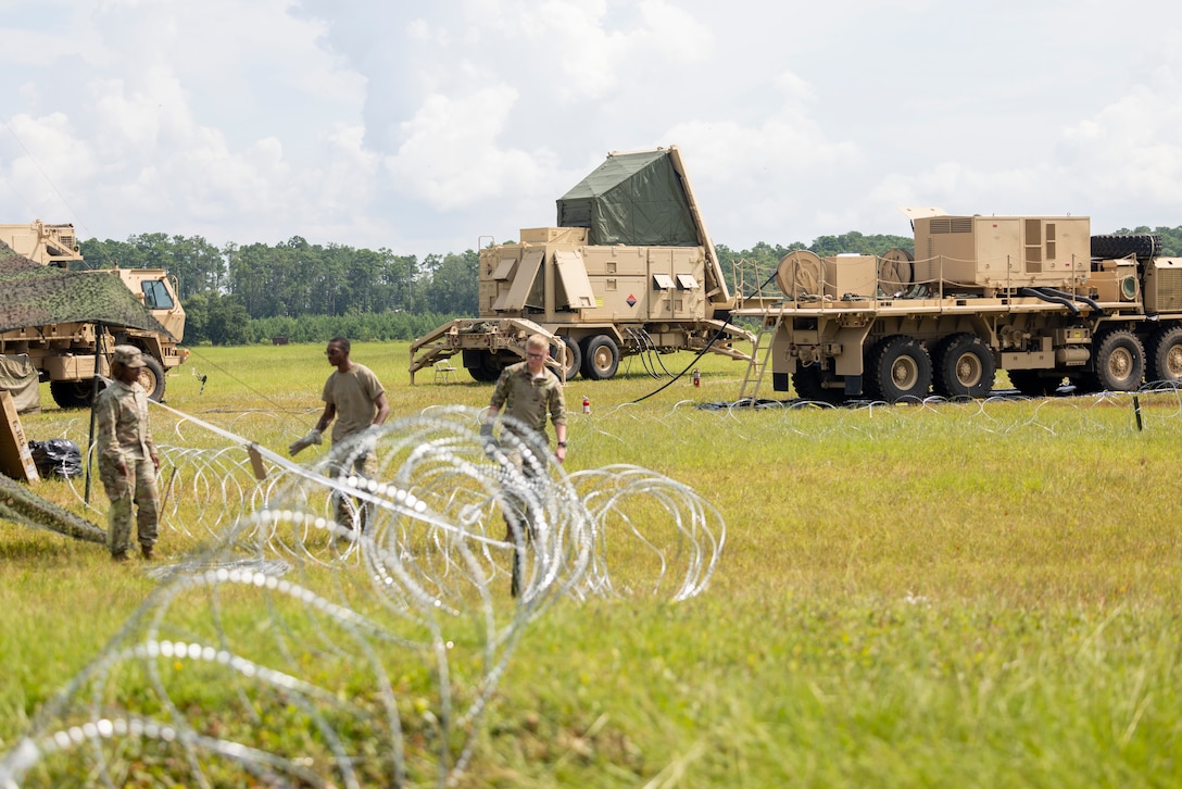 U.S. Army Soldiers with 1st Battalion, 7th Air Defense Artillery Battalion, establish a barbed-wire perimeter around the unit's assets as a part of Exercise Razor Talon on Marine Corps Air Station (MCAS) Cherry Point, North Carolina, July 25, 2023. During this exercise, fighter jets, mobility aircraft, and contingency response assets from the Army, Marine Corps, and Air Force join forces to defend MCAS Cherry Point against simulated airborne threats. (U.S. Marine Corps photo by Cpl. Jade Farrington)