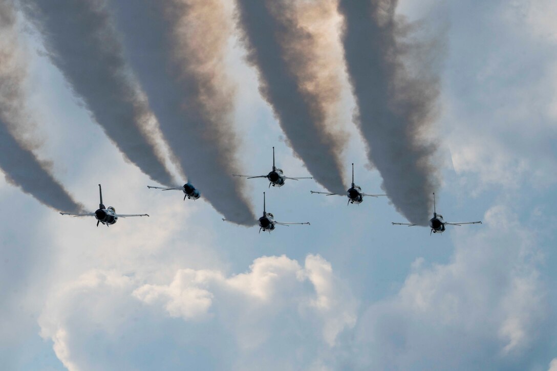 Six aircraft fly in formation as jet streams trail behind them.