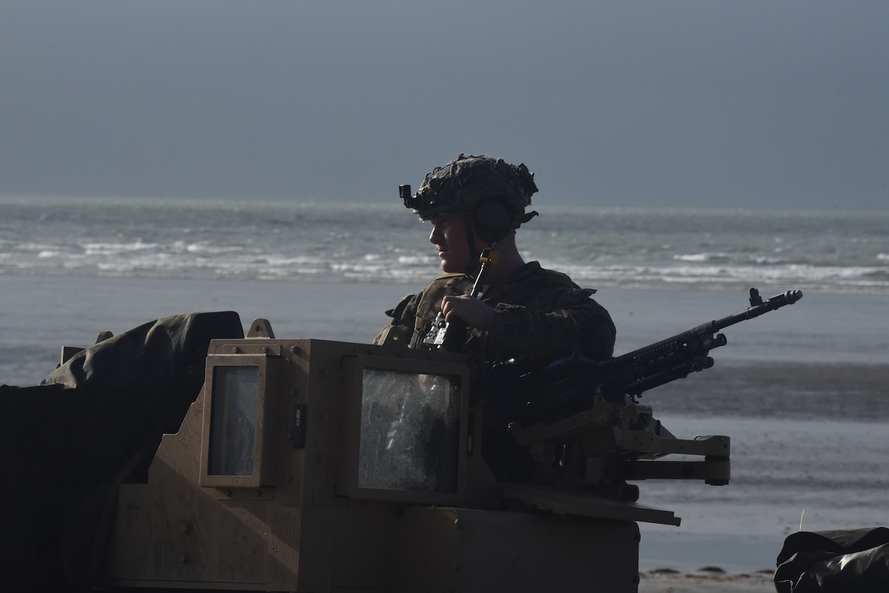 A Marine with vehicle-mounted M240B machine gun moves out from the beach.