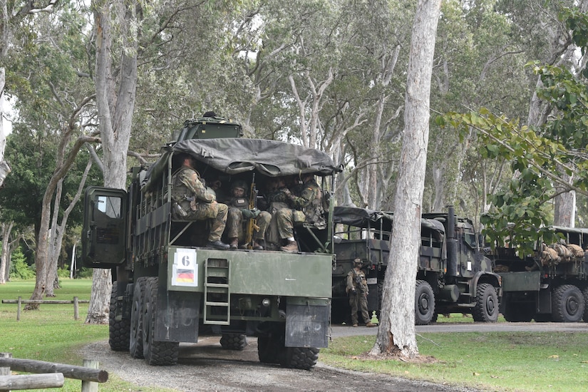 A convoy pauses on a dirt road.