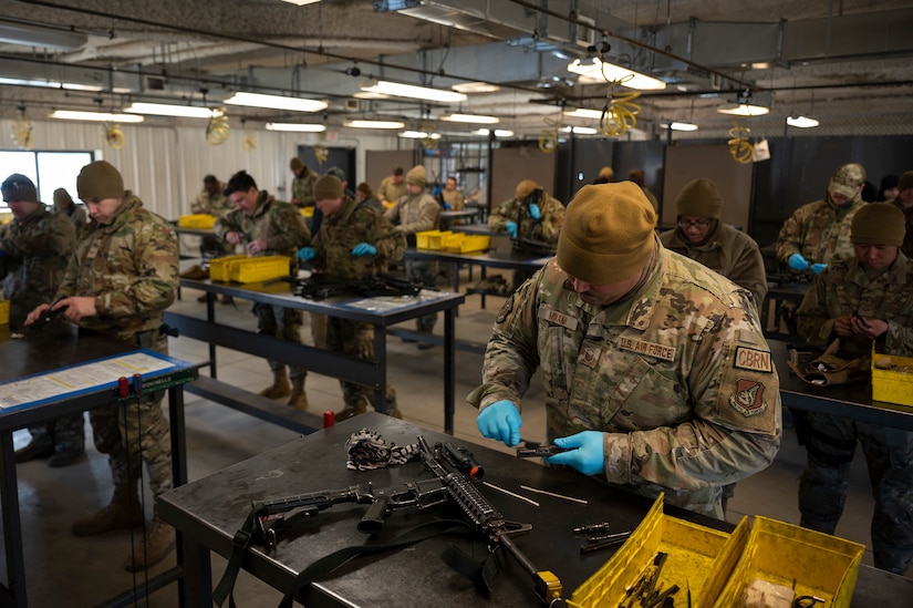 Several men work separately at benches putting together firearms.