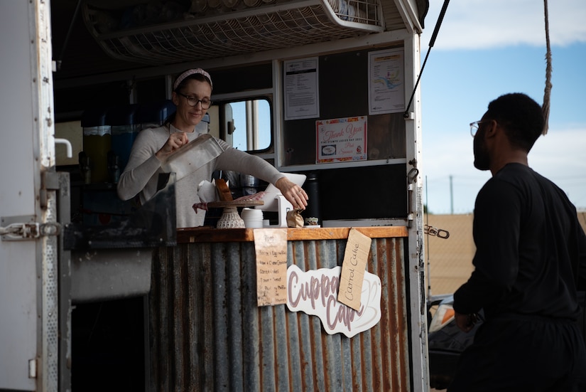 A man stands across a counter from a woman standing inside an open trailer.