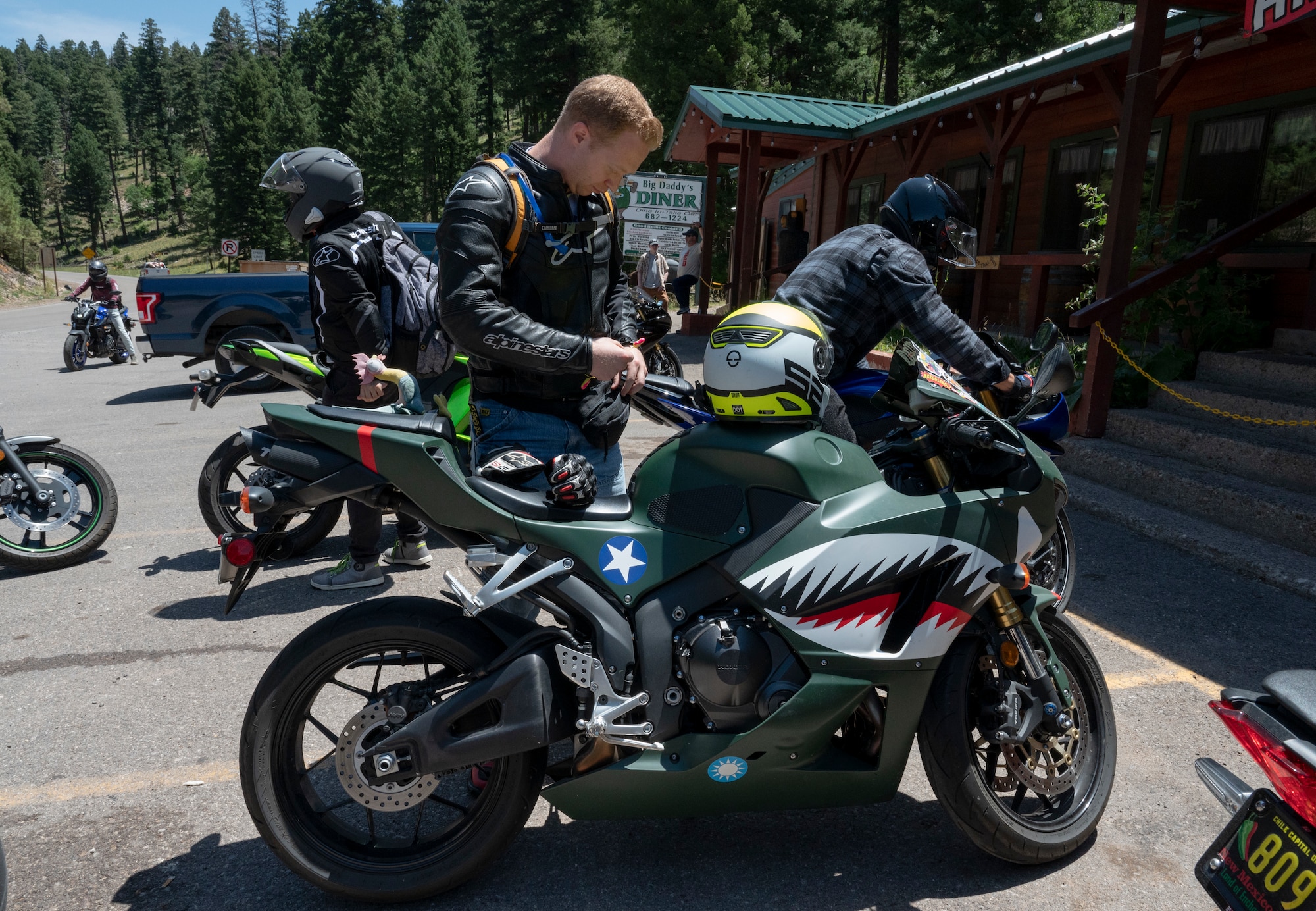 U.S. Air Force Capt. Justin Weber, 6th Attack Squadron assistant flight commander, puts on his proper protective equipment before riding during group mentorship ride in Ruidoso, New Mexico, July 21, 2023. Mentorship rides allow commanders to coordinate counseling and inspections of riders to ensure their motorcycles are safe to operate and they possess serviceable safety equipment. (U.S. Air Force photo by Airman 1st Class Michelle Ferrari)