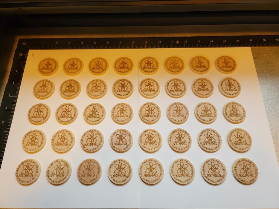 Rows of wooden coins with North Spark logo printed on them from Laser Engraver