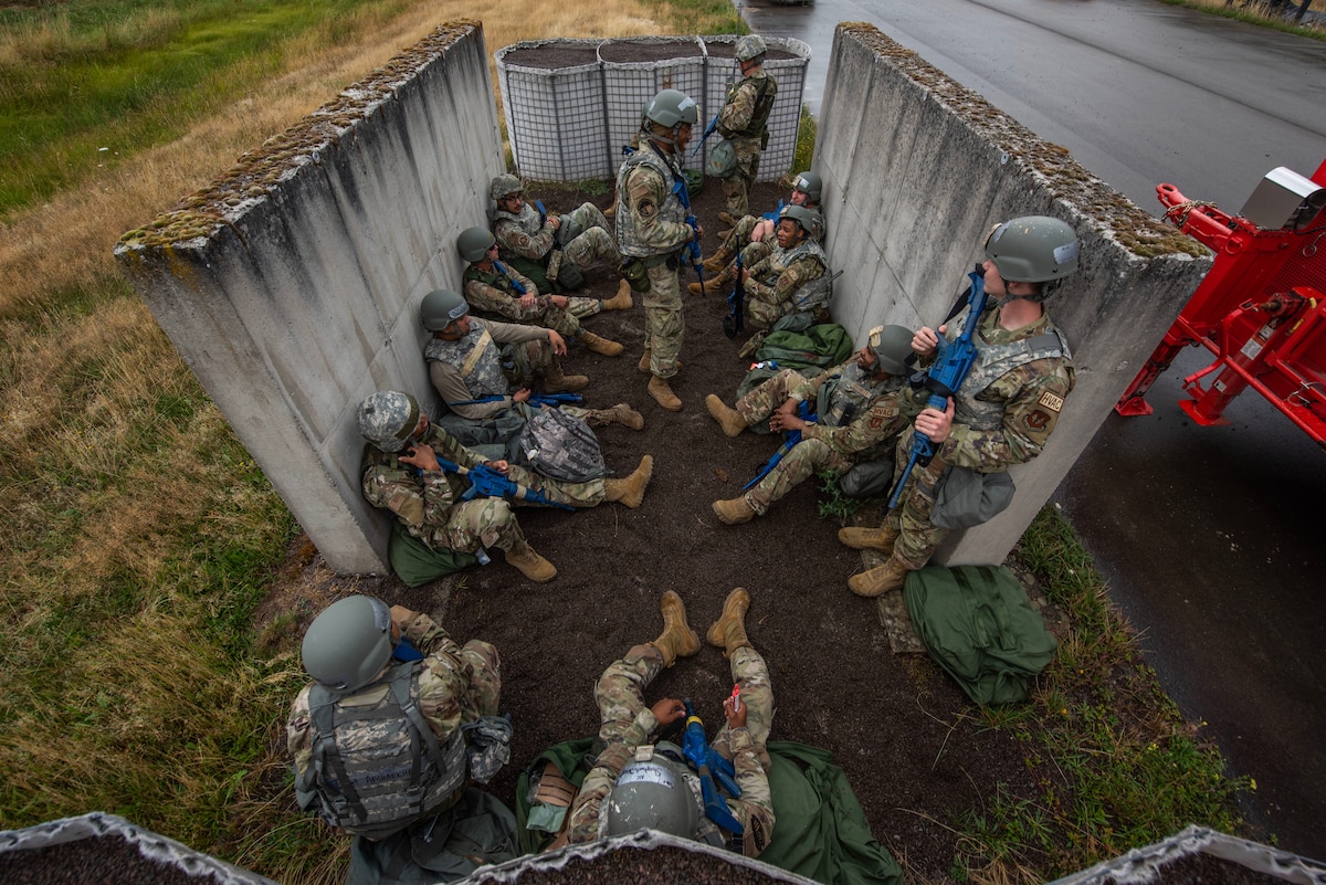 Multiple Airmen sit in a makeshift bunker during an exercise