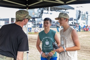 U.S. Army Staff Sgt. Rickey Mcquagge, a recruiter assigned to the Wichita Recruiting Company, passes t-shirts to a couple teenagers attending the Dam Jam Music Festival in Afton, Kansas, July 21, 2023. Mcquagge attended the Dam Jam Music Festival to assist the U.S. Army with recruitment efforts in the region. (U.S. Army photo by Spc. Steven Johnson)