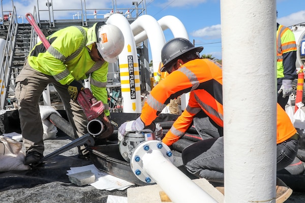 Civilians assigned to Joint Task Force-Red Hill (JTF-RH) prepare a fuel hose for connection to a fuel line in preparation for draining surge tanks at the Red Hill Bulk Fuel Storage Facility (RHBFSF), Honolulu, Hawaii, July 18, 2023.