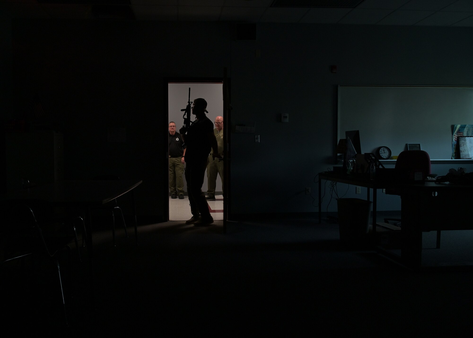 A member of the Monroe County SWAT is silhouetted in a dark room.
