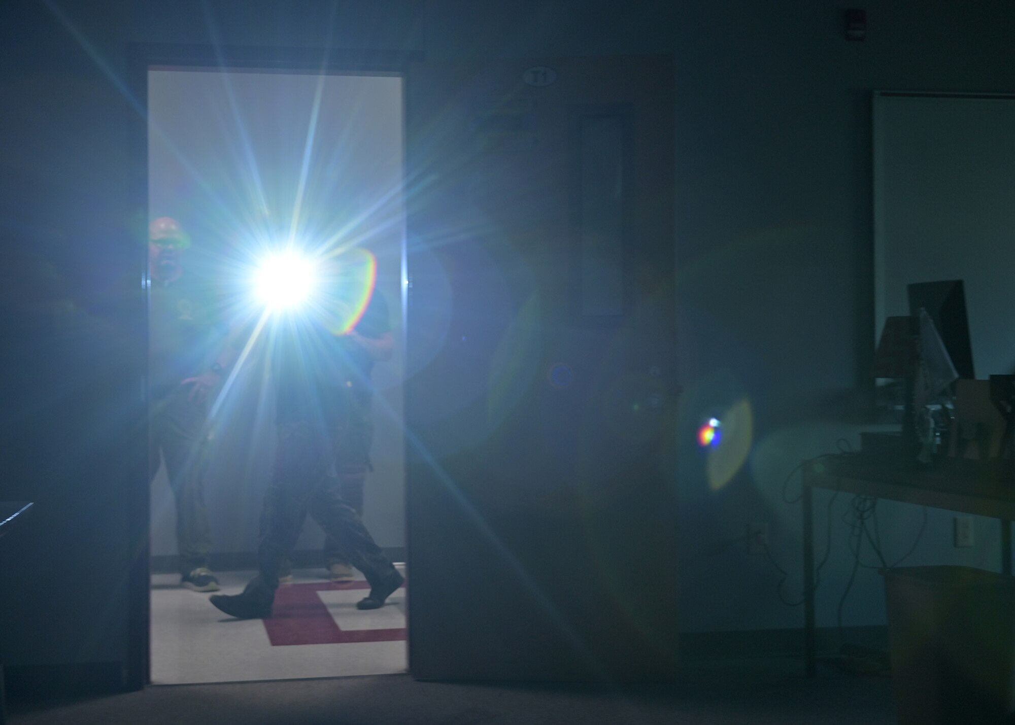 A SWAT member flashes a light into a dark room.