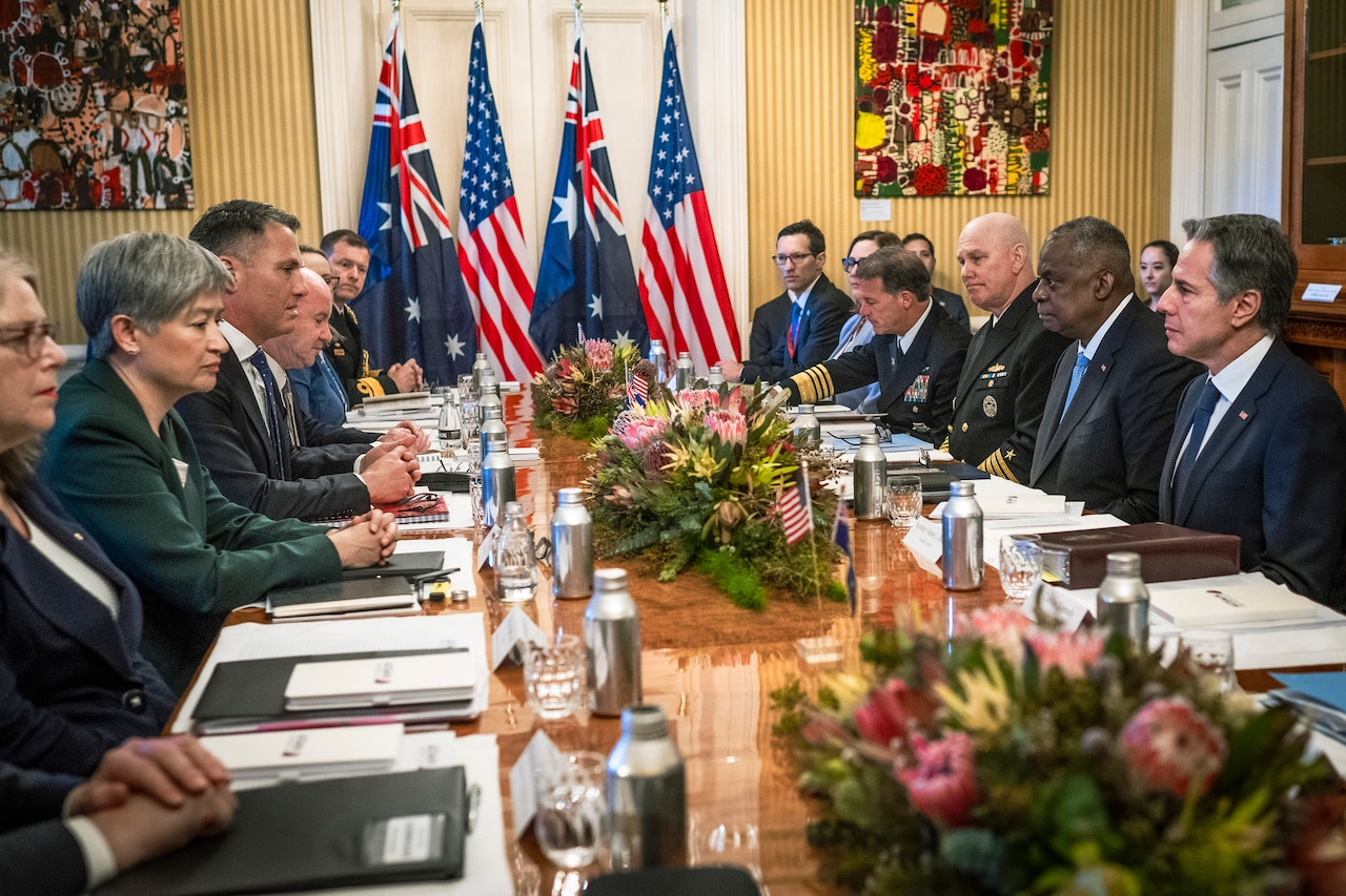 A group of people sit at a long conference table.