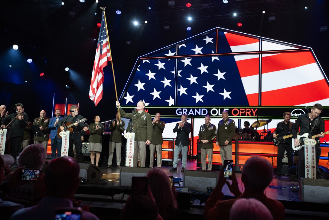 man wearing army uniform waves a flag on stage