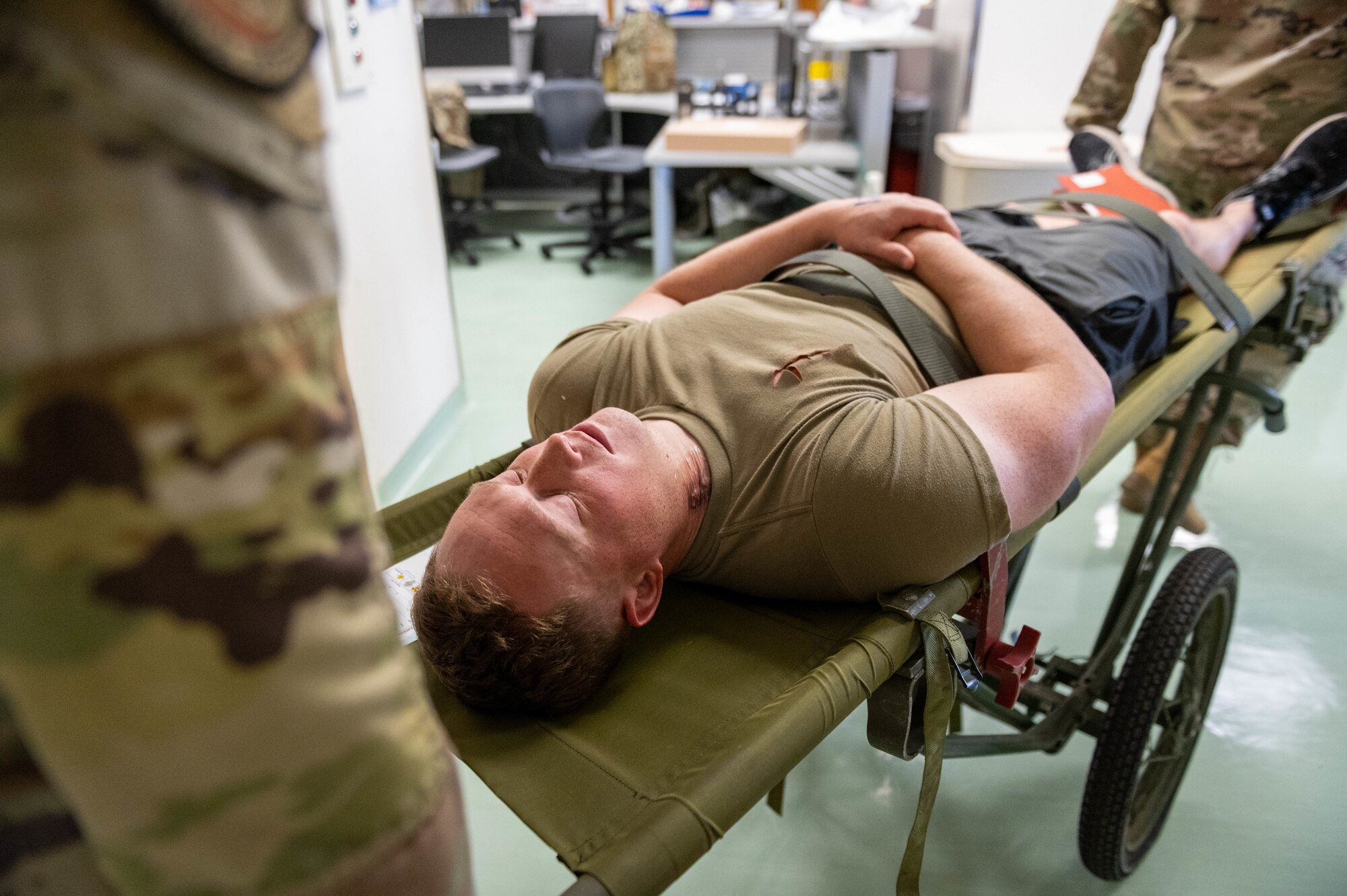 A mock patient is transported on a litter during an en route patient staging system training.