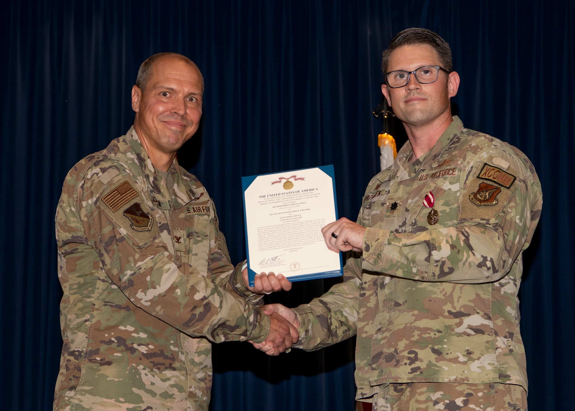 A military man gives another military man a certificate.