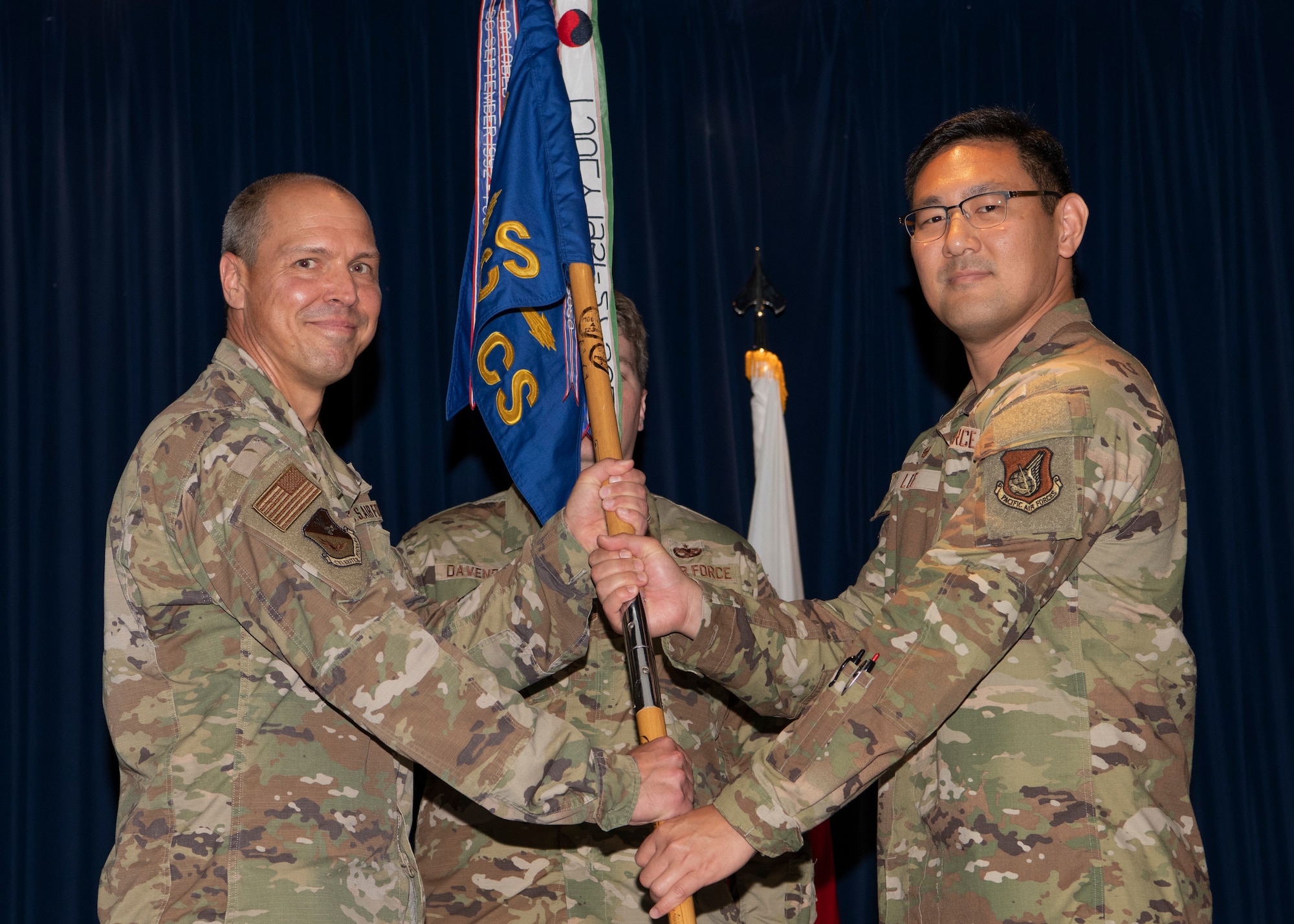 Two military members hold a guidon.