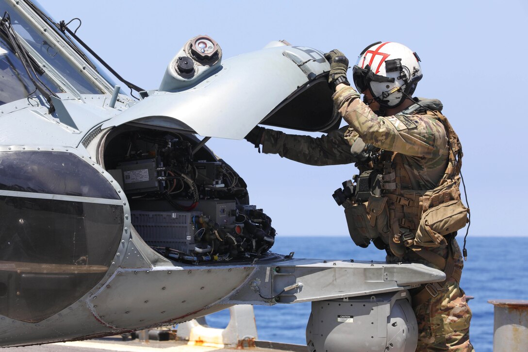 A sailor checks a helicopter.