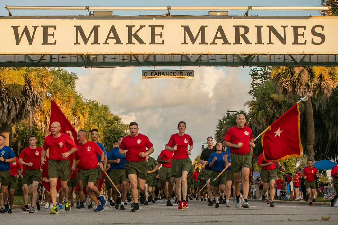 Marines run under a sign saying 'We Make Marines.'