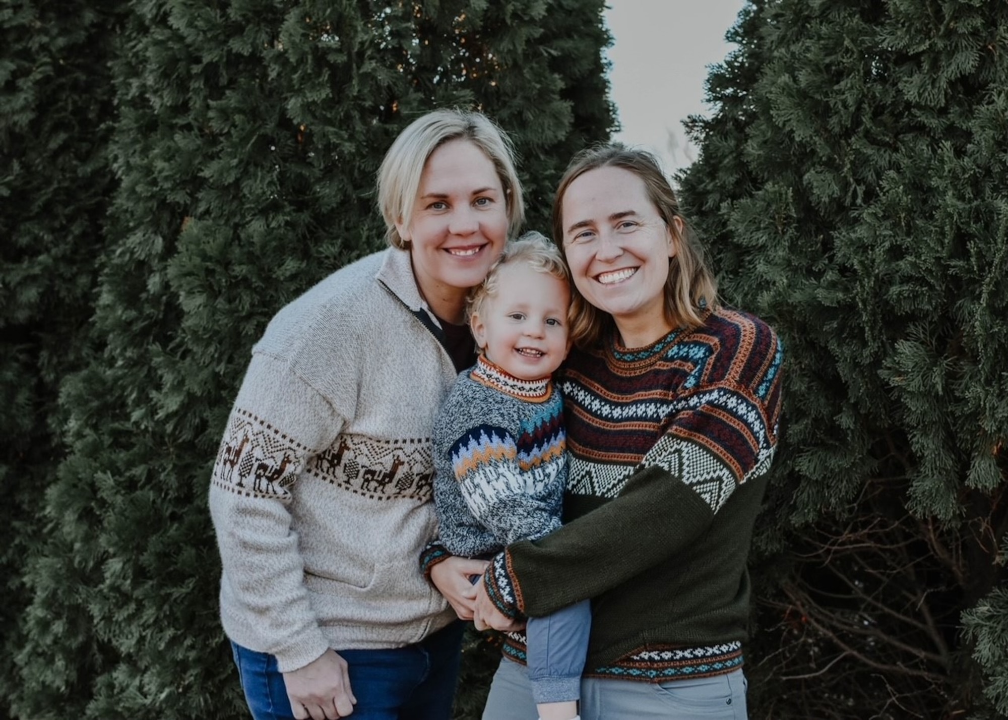 A couple holds their child for a group photo.