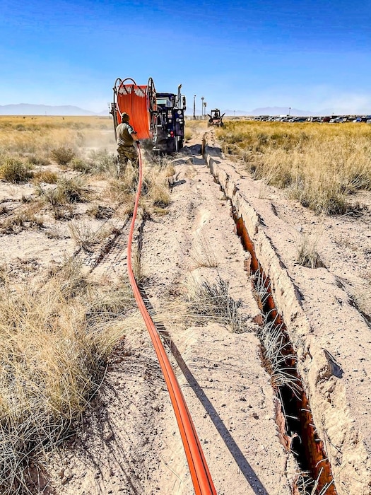 A vehicle is laying down tubing into the desert ground.